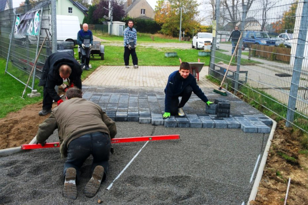 Pflasterweg zum Rasenplatz.